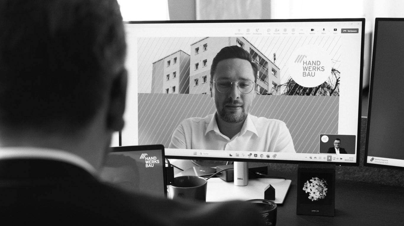 Vier Personen stehen um einen Computerbildschirm und lächeln.