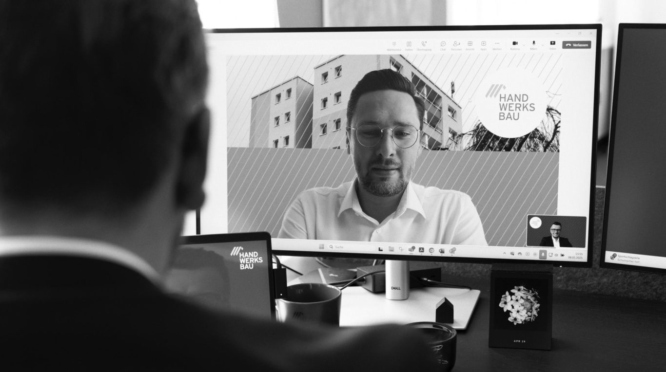 Unser Team der Handwerksbau AG Vier Personen stehen um einen Computerbildschirm und lächeln.