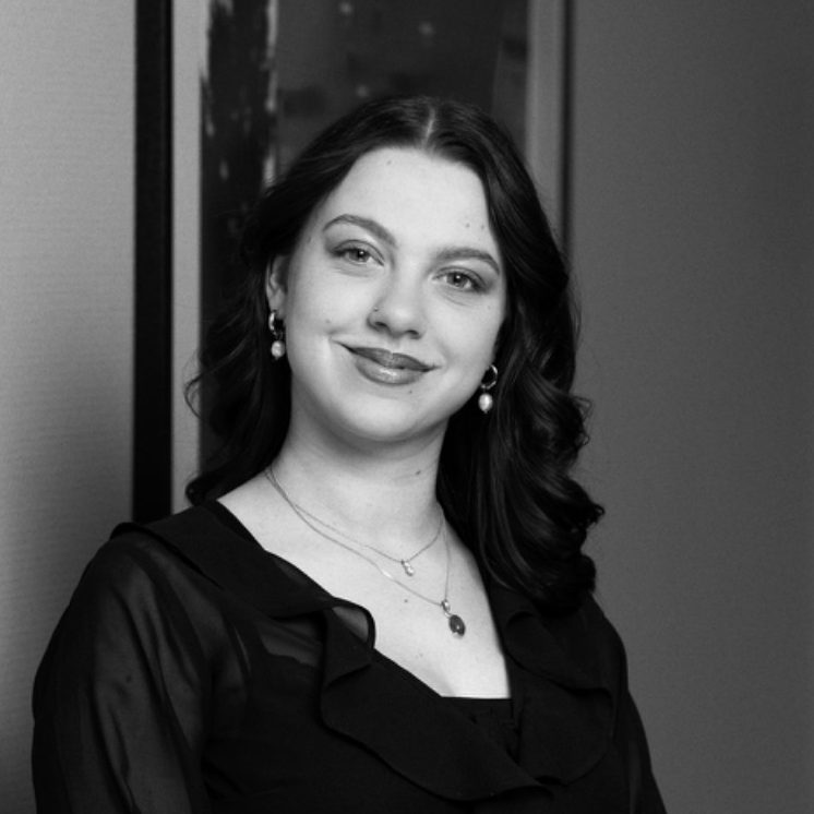 Porträt einer lächelnden Frau mit Locken in einem eleganten schwarzen Kleid.
