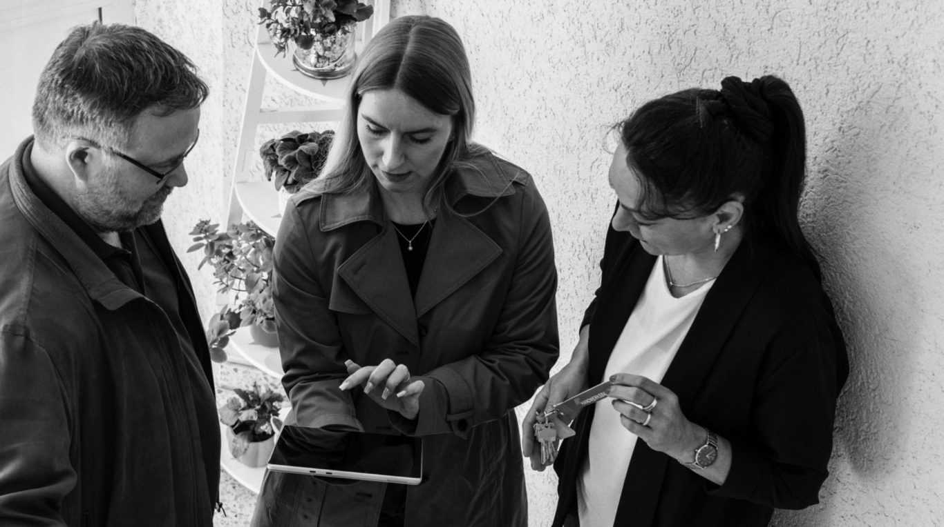 Vier Personen stehen um einen Computerbildschirm und lächeln.