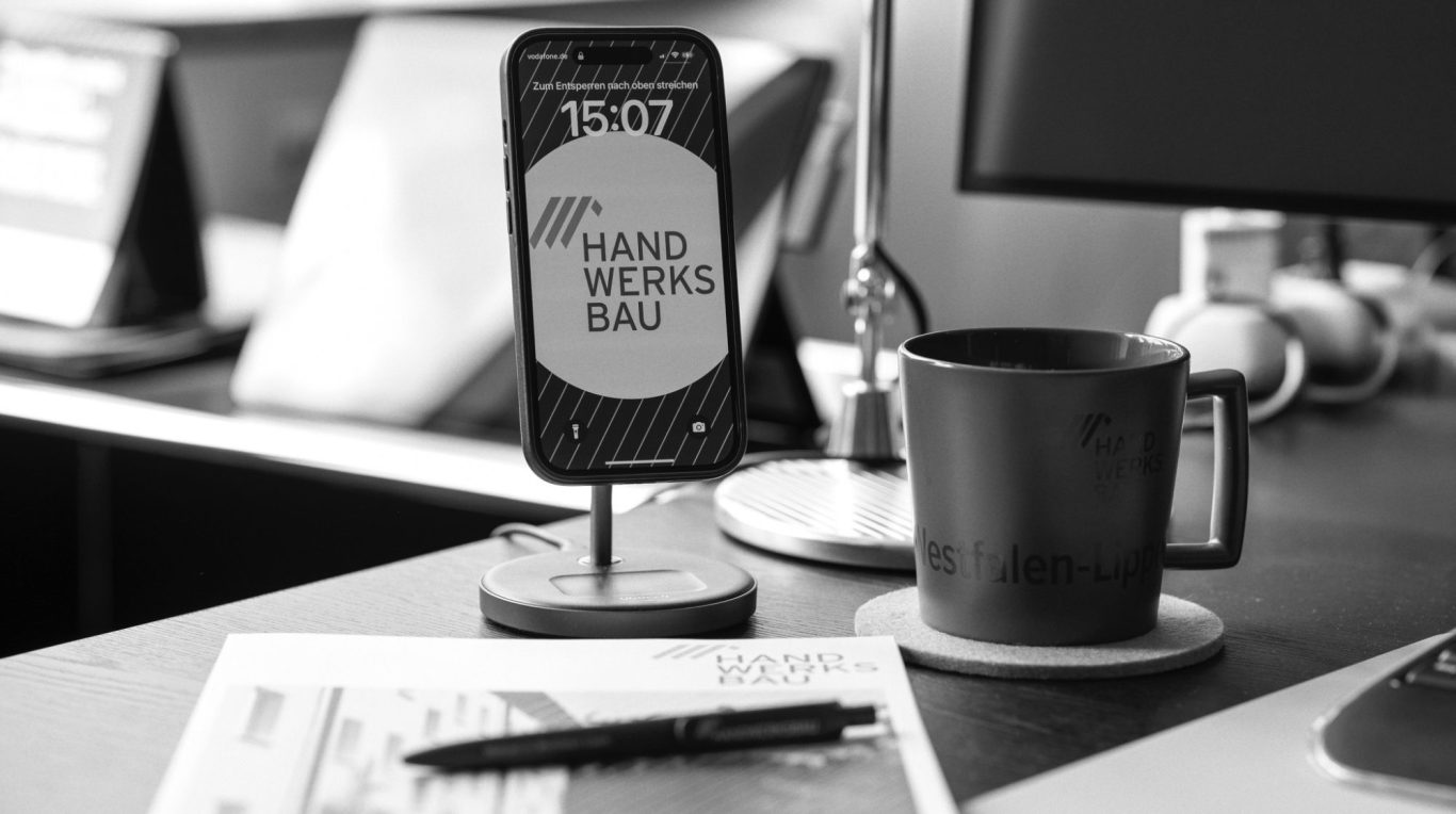 Vier Personen stehen um einen Computerbildschirm und lächeln.