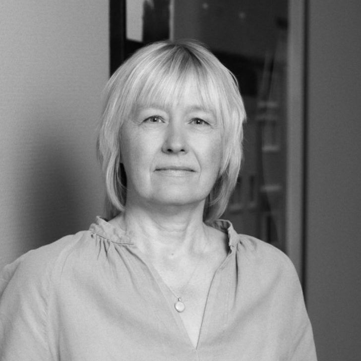 Porträt einer Frau mit blonder, kurzer Frisur und einer lässigen Bluse.