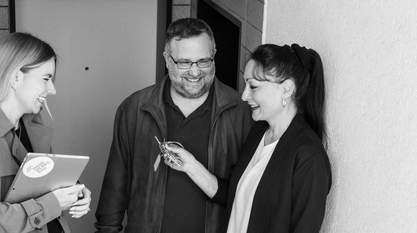 Vier Personen stehen um einen Computerbildschirm und lächeln.